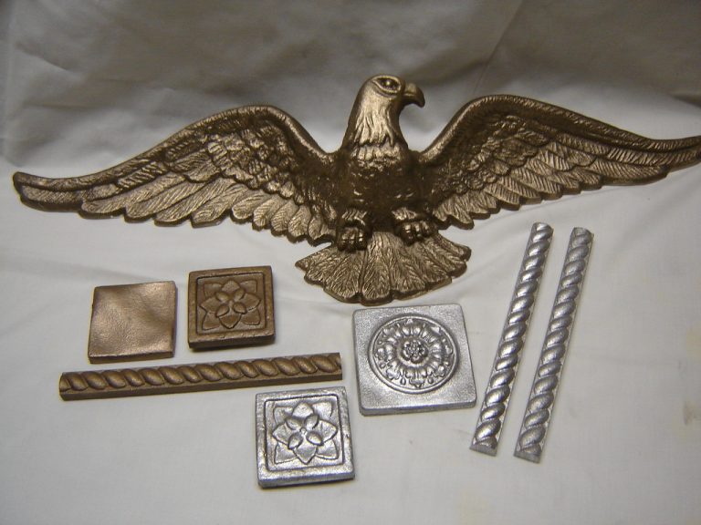 One bronze bald eagle casting surrounded by multiple other decorative castings in bronze and aluminum