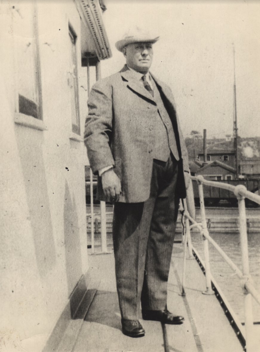 Valencia photo of William E. Warner, founder of Warner Brothers Foundry, in a suit and hat standing on a dock